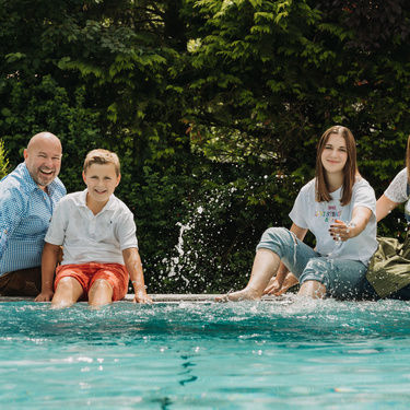 Familie gass heisst die gäste mit einem lächeln und guter laune am pool willkommen