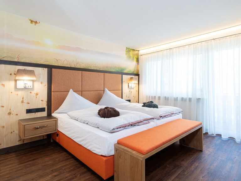 2 raum suite mit fototapete ein blick übers kornfeld auf dem bett liegen bademantel die möbel sind in hellen braun mit orange gehalten