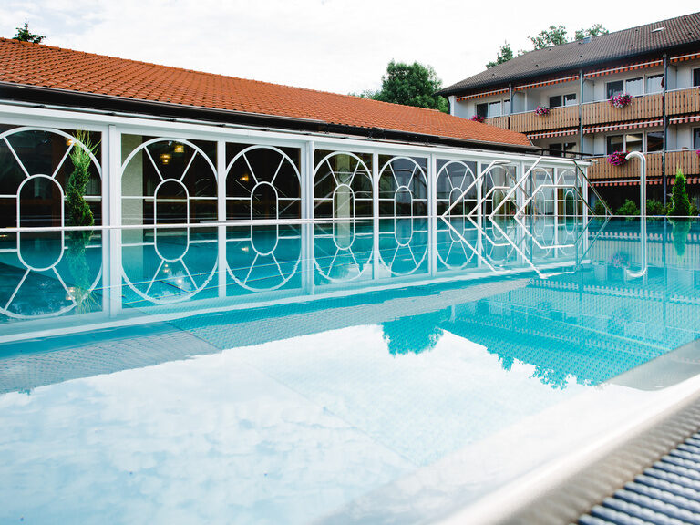 der wintergarten spiegelt sich im blauen wasser des thermalaussen becken