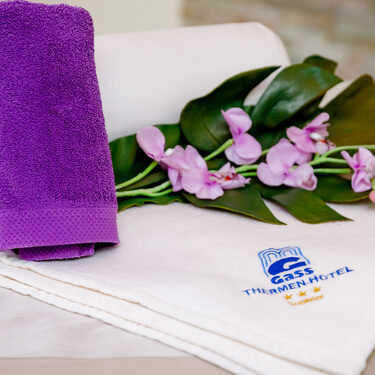 auf dem handtuch mit gass logo liegen orchideen im ein kleines lila handtuch