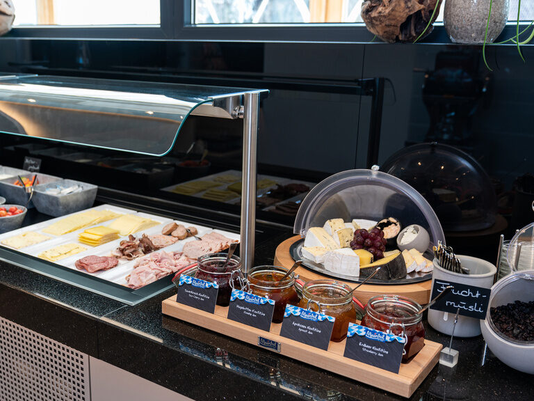 blick auf das buffet mit wurst und käse sowie käseplatte mit verschiedenen hartkäse frischkäse davor 4erlei marmelade gläser