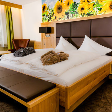 deluxe zimmer mit sonnenblumen als tapete über dem bett in grün und braunen farben mir sitzbank vorm bett