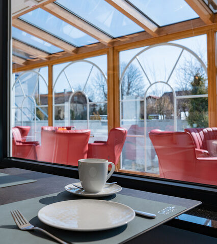 zeitlos moderner licht durchfluteter frühstücksraum mit blick durch den wintergarten zum außenbecken