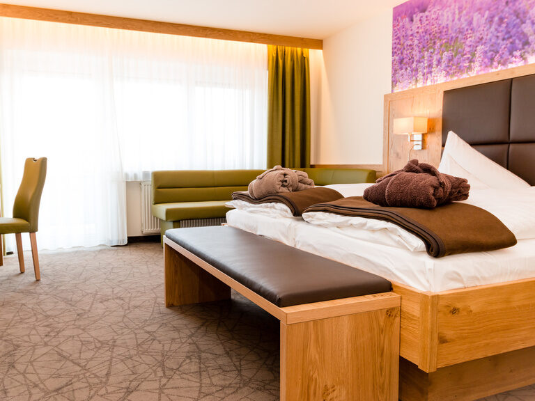 sanfte braun und grün töne schreibtisch eckbank sowie lila farbener wandtapete mit bademantel auf dem bett für einen erholsamen aufenthalt