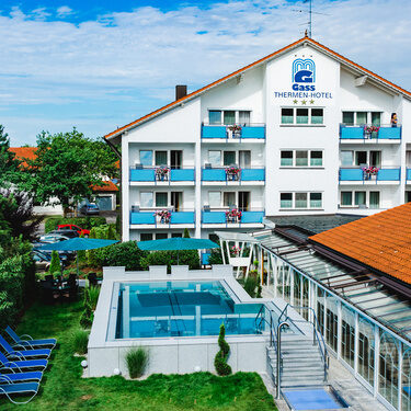 detailaufnahme vom Appartment Haus über pool mit blauen klaren wasser zum hotel wo am balkon die blumen blühen
