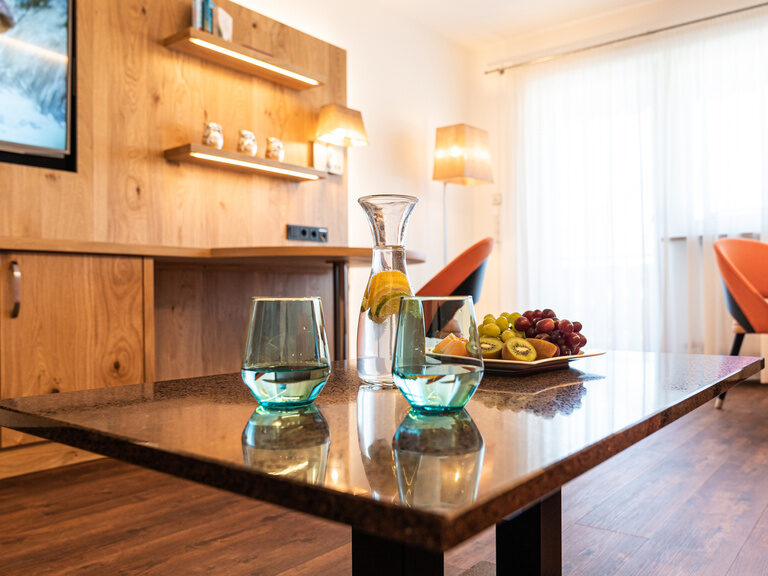 2-raum-suite-wohnbereich-ohne-teppich-mit-orangen-möbeln-obstteller-und-zitronenwasser