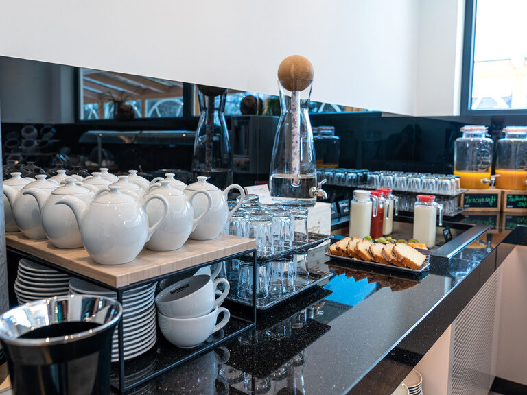 glänzendes-schwarzes-granit-im-neuen-buffetraum-mit-saftbar-einer-teestation-kuehltheke-und-gesundem-zirbenwasser