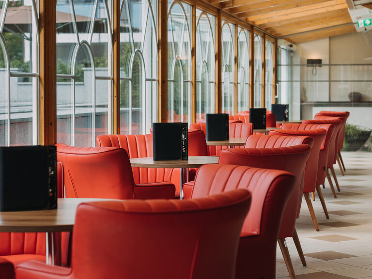 wintergarten-mit-gemuetlichen-zum-verweilen-einladenen-roten-stuehlen-fuer-kleine-snacks